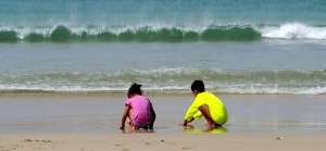 Watching the kids, content with life, as they play on the beach.